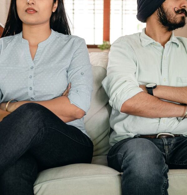 A couple sits with arms crossed and backs turned, reflecting the emotional distance that signals they've given up on each other.