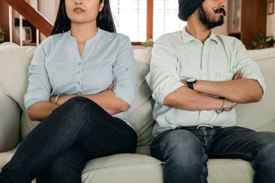 A couple sits with arms crossed and backs turned, reflecting the emotional distance that signals they've given up on each other.