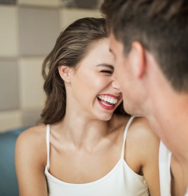A woman beams with delight as a man close to her shares a kind compliment about her looks.