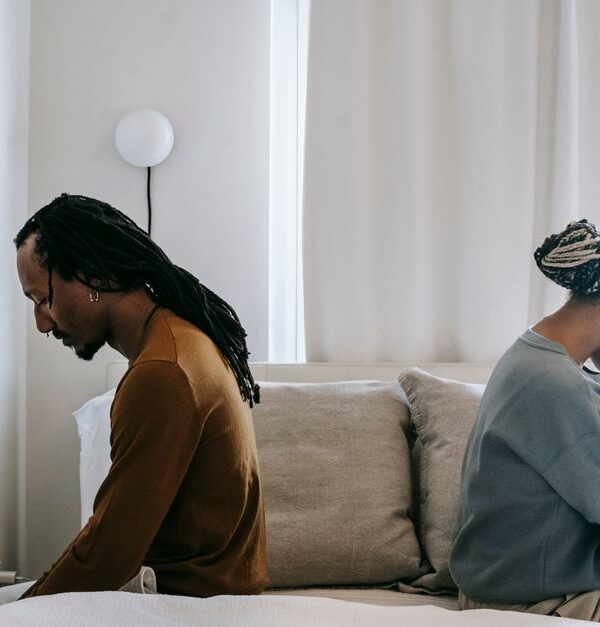 A couple sits back to back in silence, reflecting the quiet emotional distance that often leads men to leave a relationship.