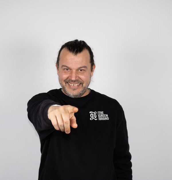 A man grinning slyly while pointing at the camera, as if caught in a white lie.