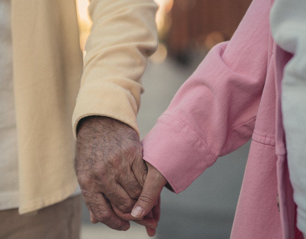 An older couple holding hands on an evening walk