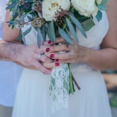 An older bride and groom hold hands around a wedding bouquet, reflecting lessons learned before marriage later in life.