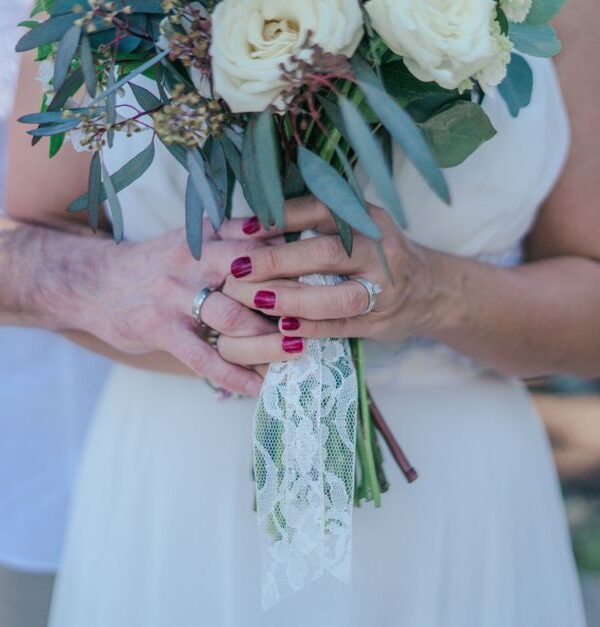 An older bride and groom hold hands around a wedding bouquet, reflecting lessons learned before marriage later in life.