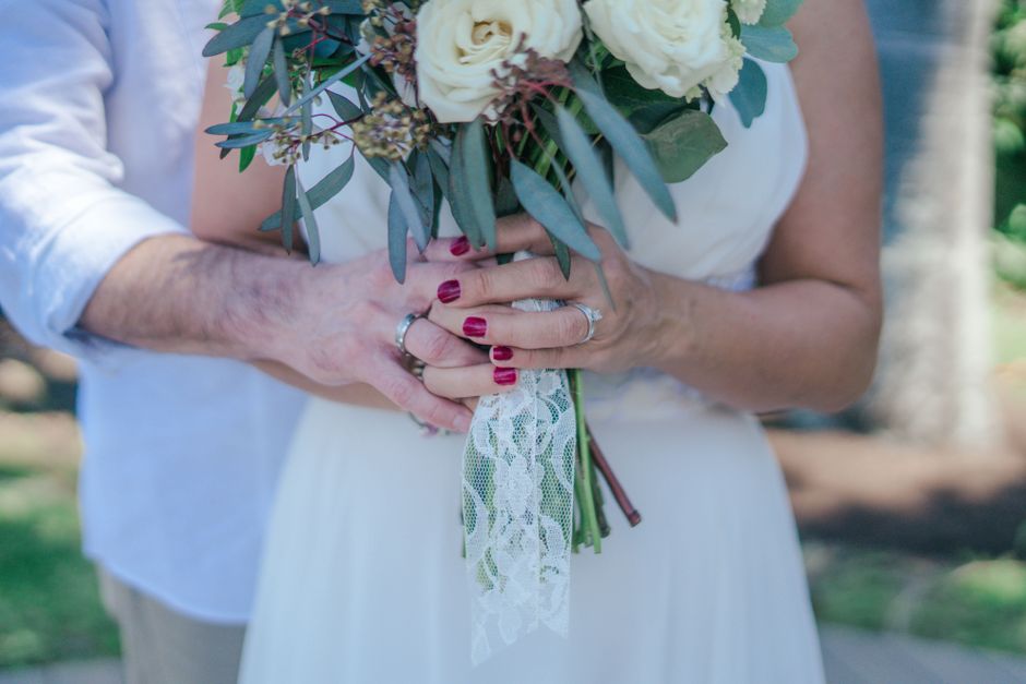 An older bride and groom hold hands around a wedding bouquet, reflecting lessons learned before marriage later in life.