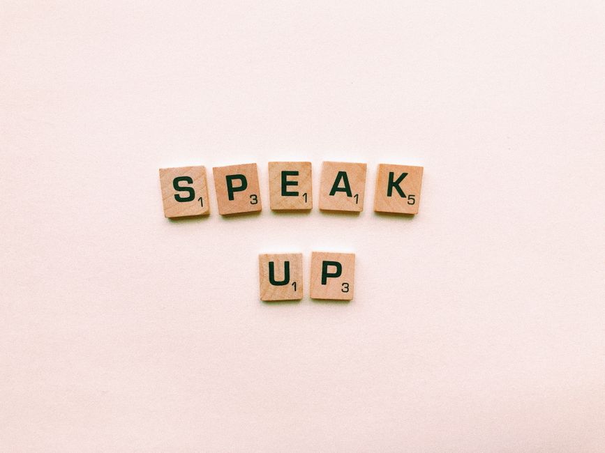 Wooden letter tiles spelling "Speak Up," reminding married couples that communication matters since nobody can read your mind.