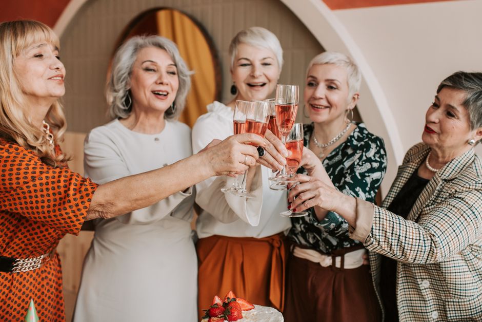 Group of women over 50 raising a toast together, celebrating their lasting friendship.