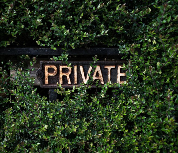A "Private" sign nestled among greenery, symbolizing the importance of keeping some things to yourself in marriage.