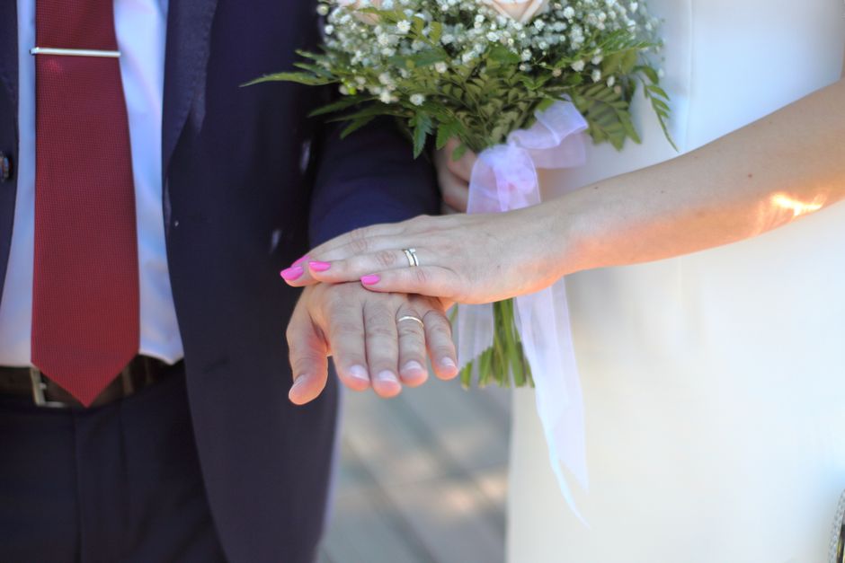 A married couple holding hands and showing their wedding rings, symbolizing partnership rather than keeping score in marriage.