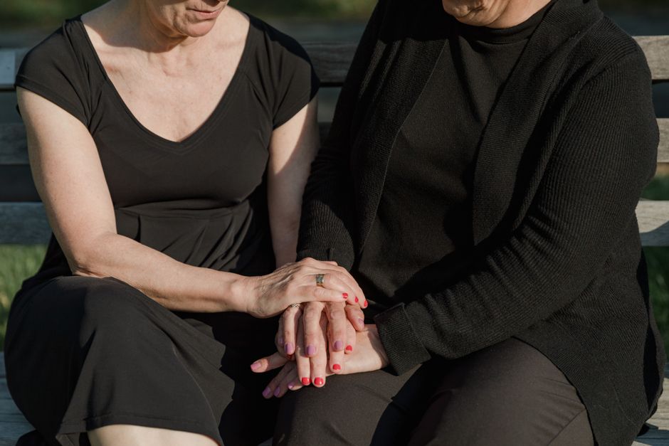 Two women over 50 holding hands in a gesture of support and honest conversation.
