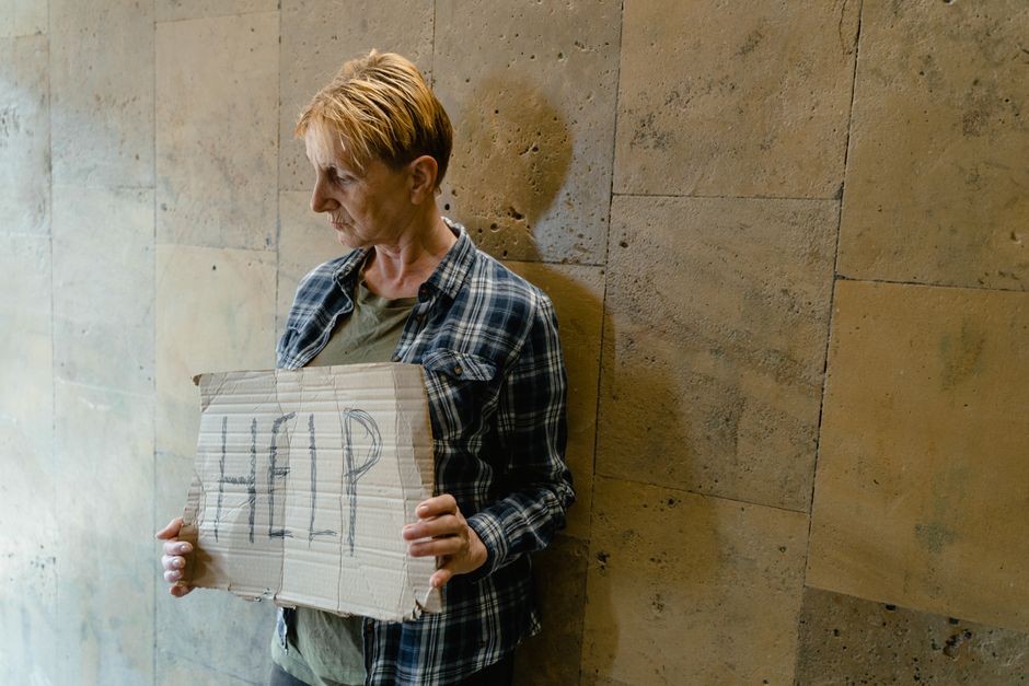 A woman holds up a handwritten "help" sign, symbolizing the need for outside support with certain marriage problems.