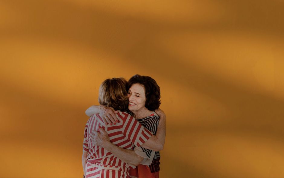 Two women share a warm, affectionate hug, reflecting the quiet kindness that sustains a lasting marriage.