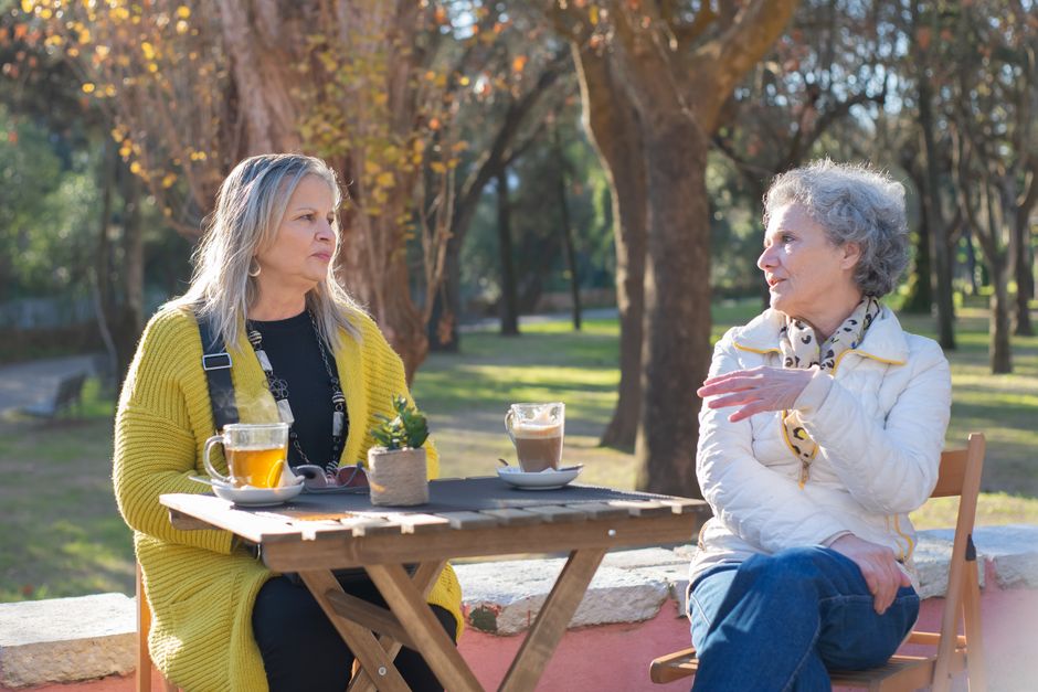 Two women over 50 having a candid conversation over coffee, discussing important life lessons like talking about money before marriage.