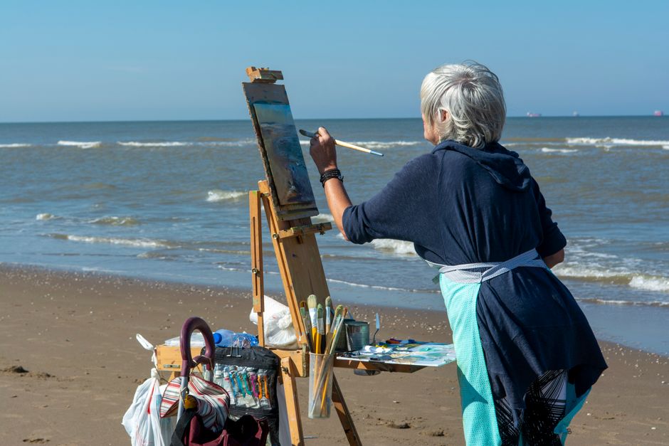 A woman over 50 enjoys her own hobby of painting by the sea, showing the importance of keeping personal passions alive even after marriage.