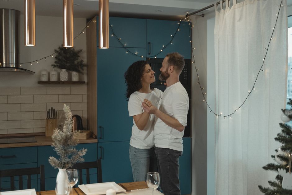 A couple shares a joyful dance in their kitchen when a favorite song plays, a timeless habit happy couples have embraced since the '60s.