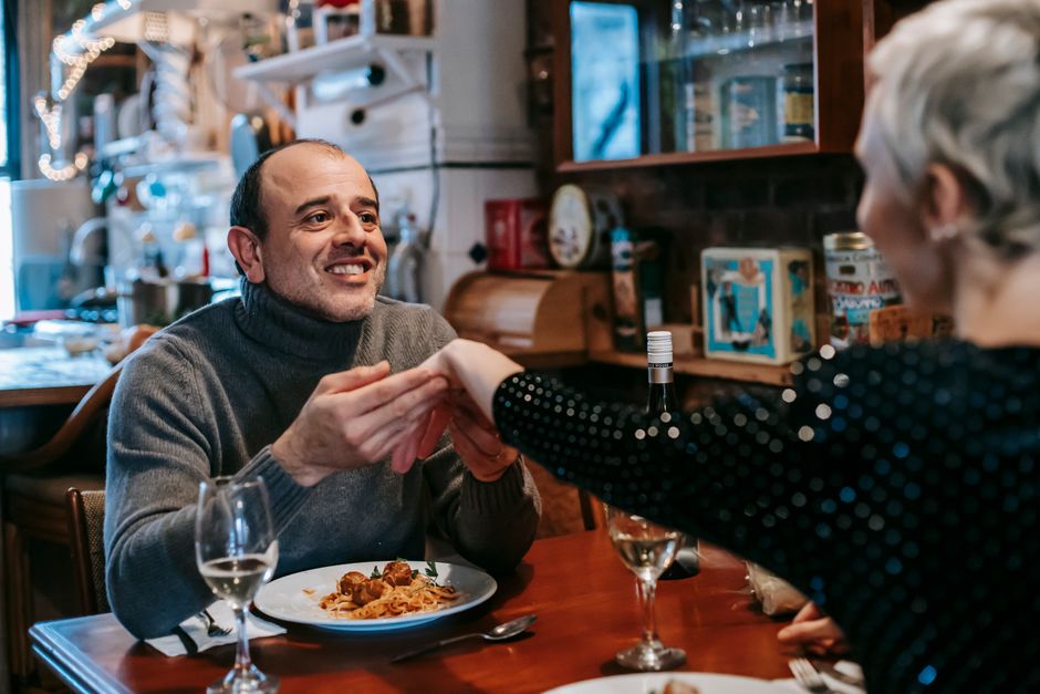 A mature husband and wife share a thank-you touch over a simple homemade meal, embodying the small daily appreciation that keeps long marriages strong