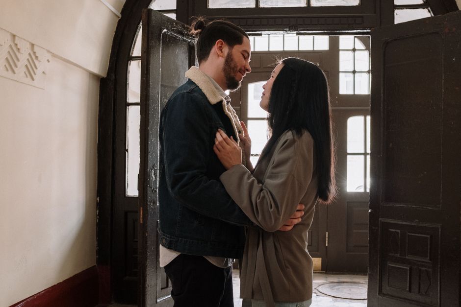 A couple shares a kiss at the doorway, a timeless habit many '60s couples still swear by.