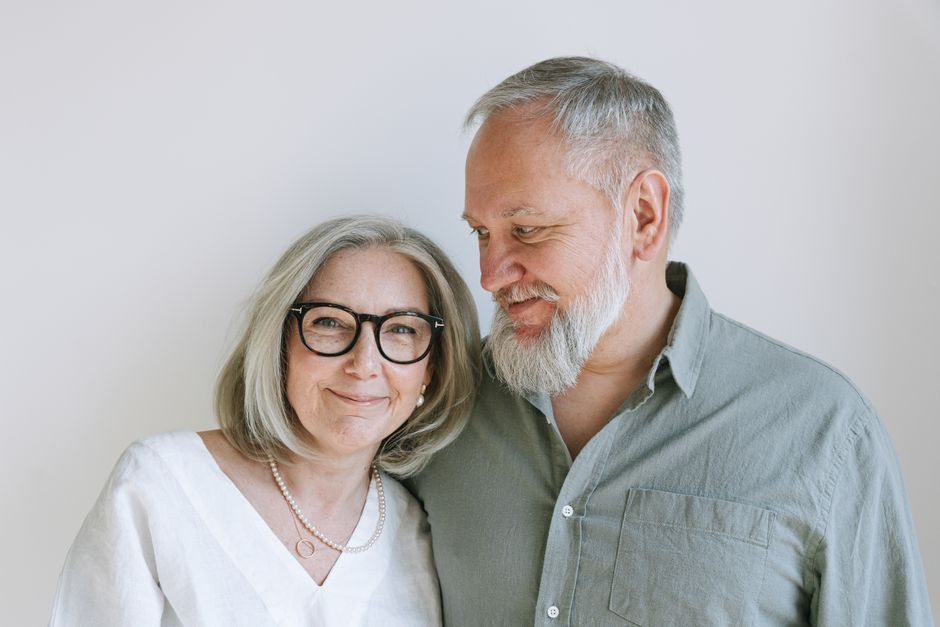 An older married couple smiling affectionately at one another, embodying the patience and calm that comes from letting small irritations go