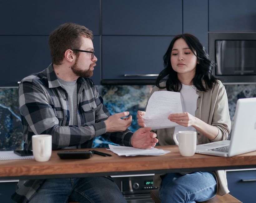 A couple openly discusses their finances at the kitchen table, echoing the old-fashioned habit of talking about money regularly