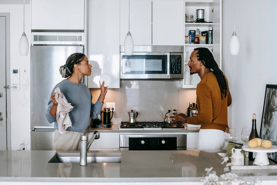 A couple arguing intensely in their kitchen, illustrating the tension that can arise when a partner makes unreasonable demands like controlling your every minute.