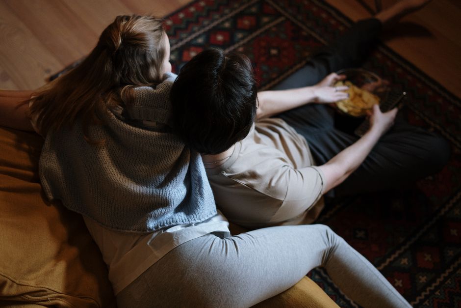 A couple cozied up together under a blanket, enjoying quiet everyday time side by side.
