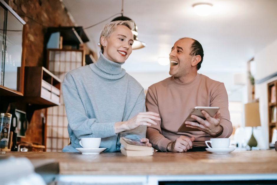 A man and woman share a laugh over coffee, enjoying a moment of genuine connection and humor.