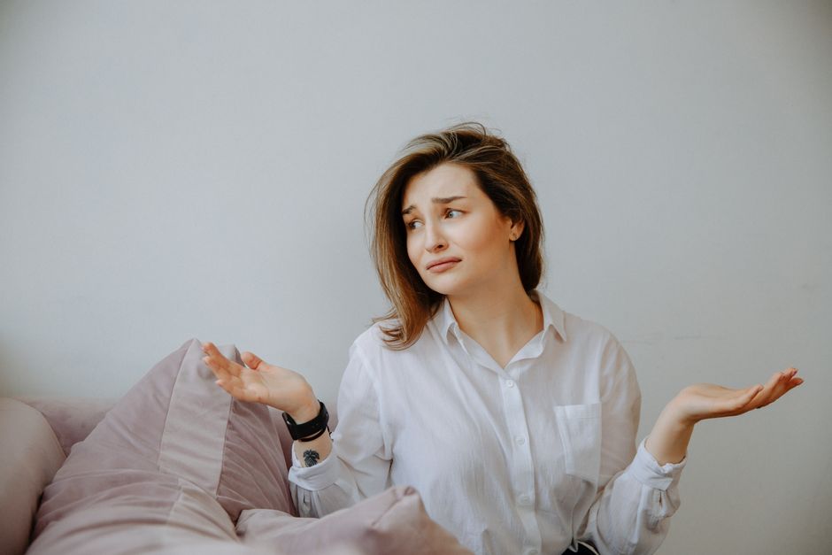 A woman shrugs with a dismissive, confused look, as if brushing off an excuse like "everybody does it."