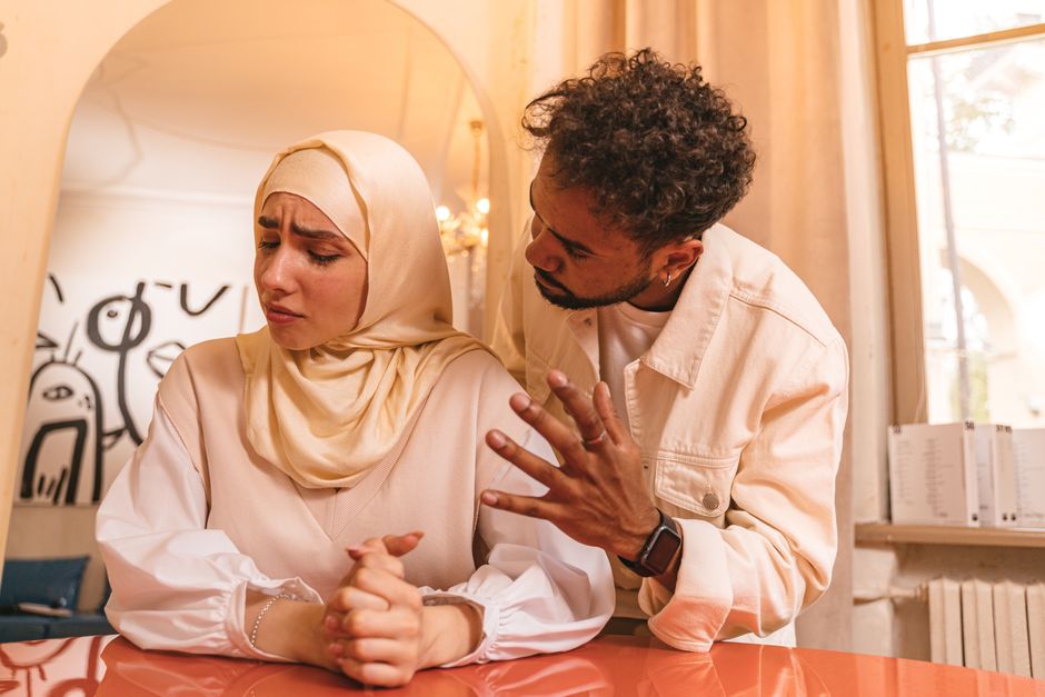 A woman avoids eye contact while a man gestures, seemingly trying to explain away something she clearly saw.