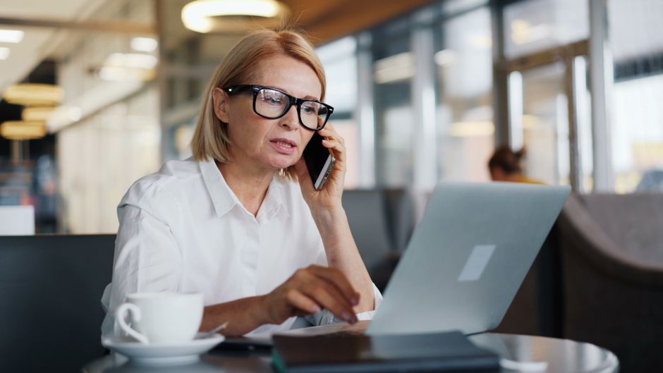 A woman on the phone appears distracted and evasive while working on her laptop, hinting at selective memory.