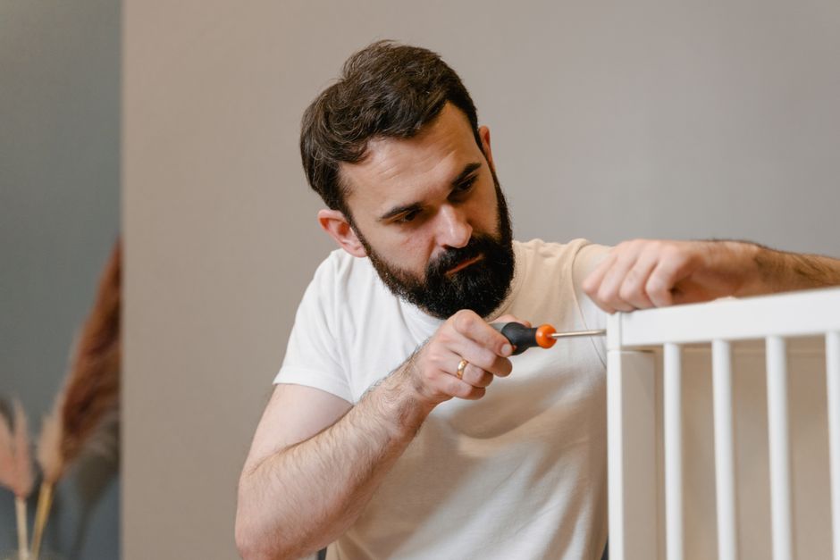 A husband using a screwdriver to fix and assemble furniture, showing he still cares enough to maintain things around the house.