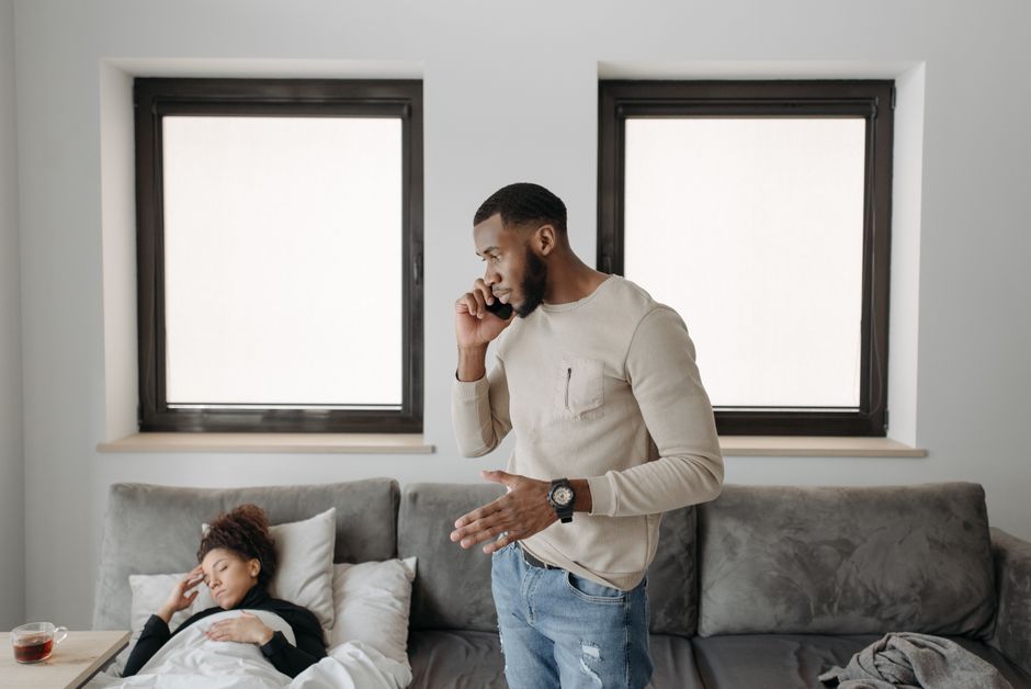 A man talks on the phone about his relationship while his partner lies on the couch feeling hurt and left out of the conversation.