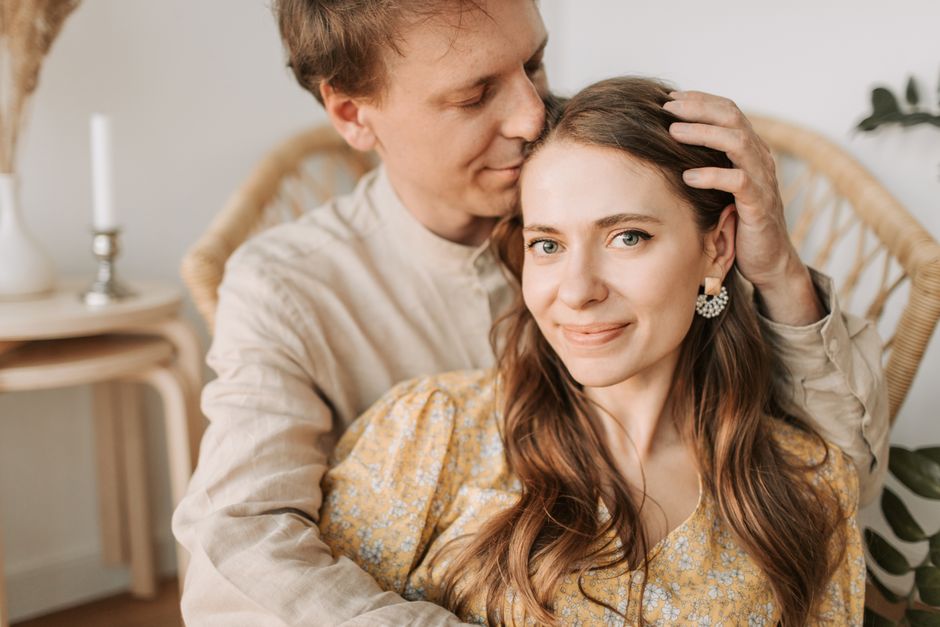 A man gently kisses his smiling partner's head, a quiet gesture of pride and affection.