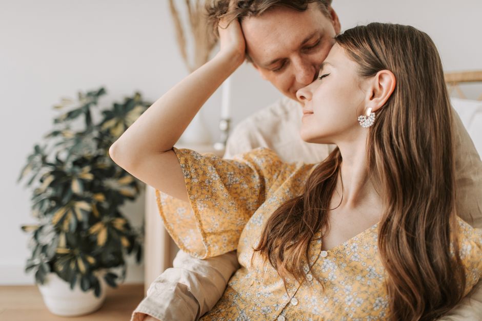 A man gently kisses a woman's forehead, showing quiet affection and attraction between them.
