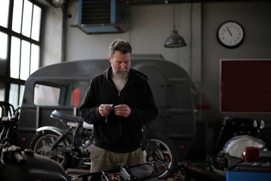 A man absorbed in his own private hobby space, surrounded by motorcycles that are entirely his own.