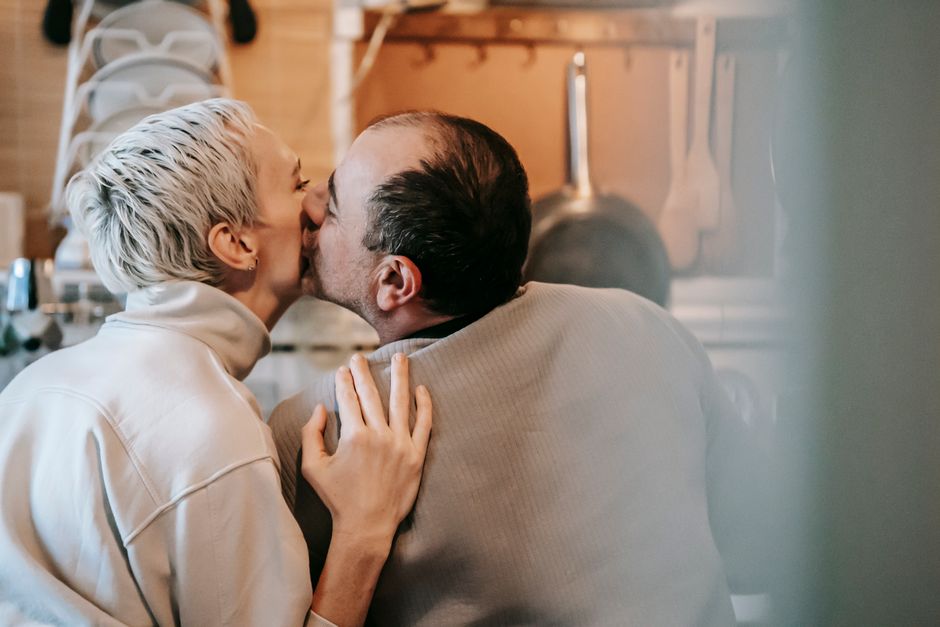 A woman tenderly kisses her husband, showing him she still chooses him after all these years.