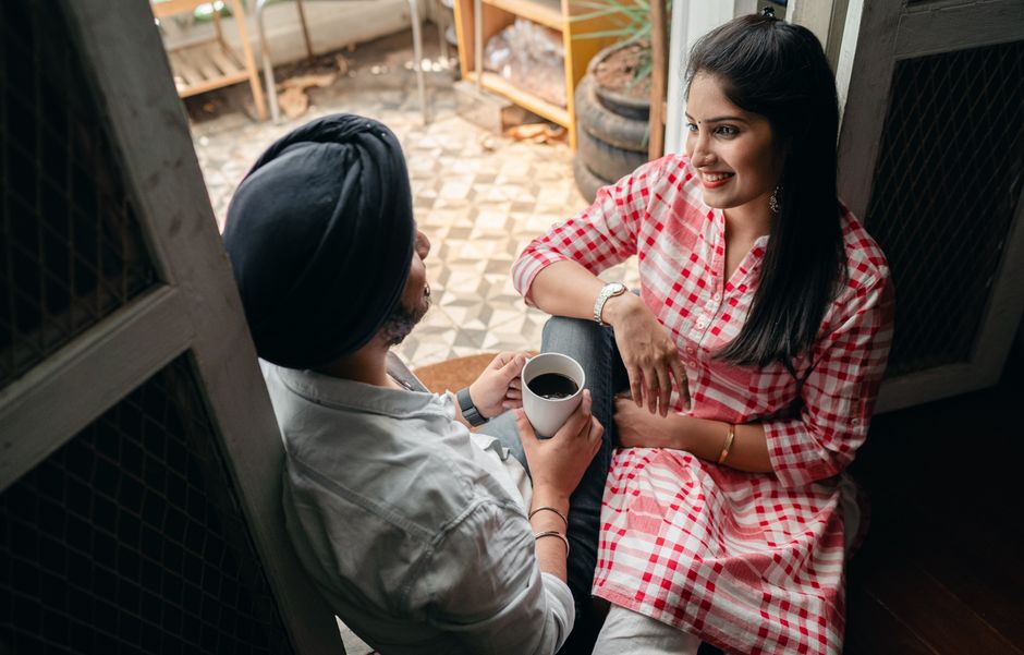 A husband and wife share coffee and conversation together, focusing on each other.