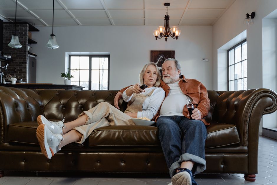 A husband and wife cuddle on the couch together, remote in hand, as they pick a show to watch together on purpose.
