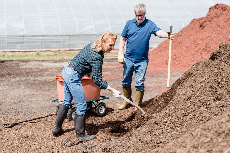 A husband and wife work side by side outdoors, shoveling soil together as a way to reconnect.