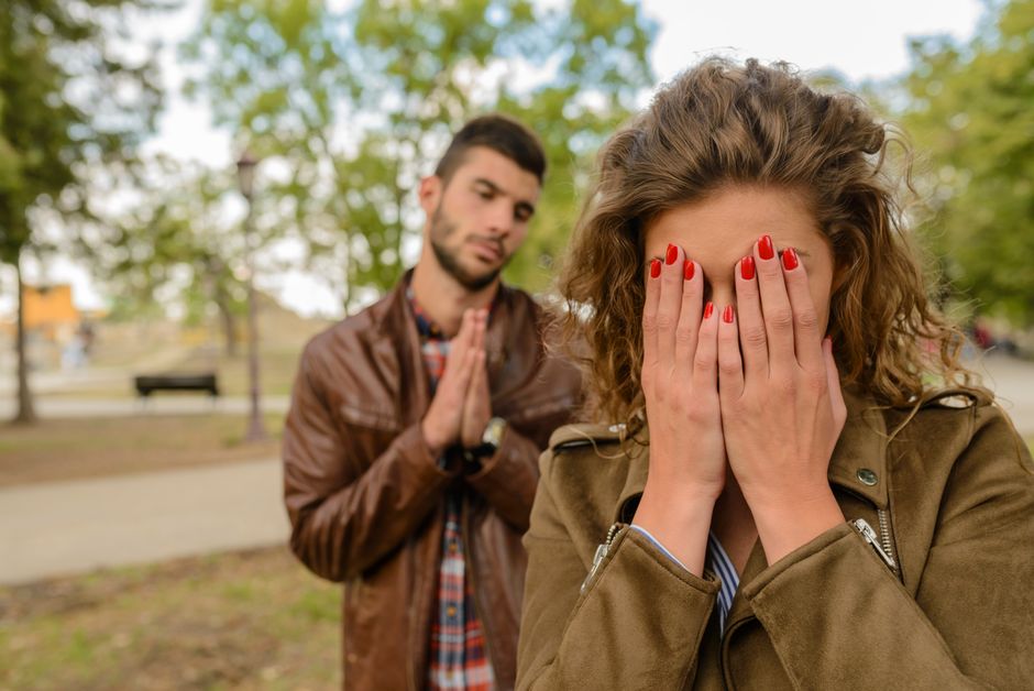 A man pleads with clasped hands while a woman covers her face in frustration, illustrating the struggle of apologizing without excuses.