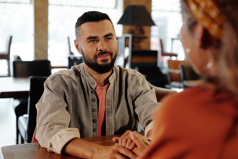 A man listens intently and holds his date's hands while she talks, showing genuine interest in what she's saying.