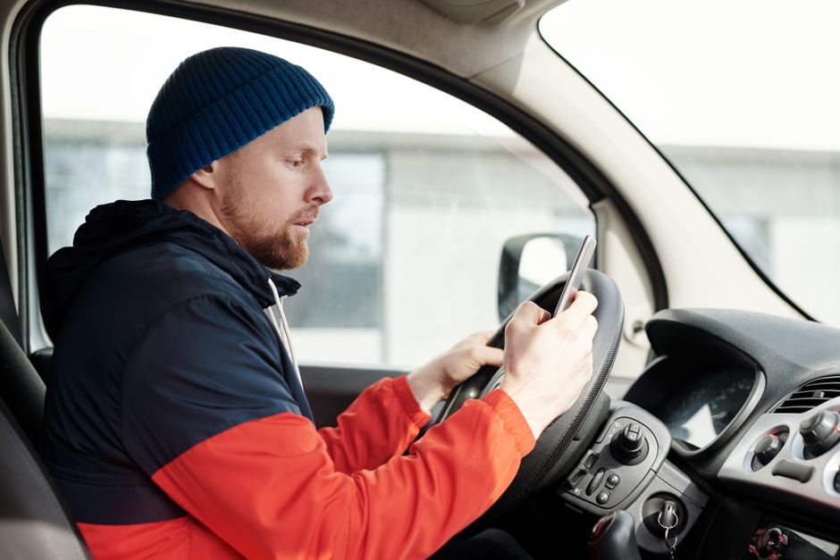 A man secretly glances at his phone while driving, hinting at hidden truths he hopes you'll never catch.