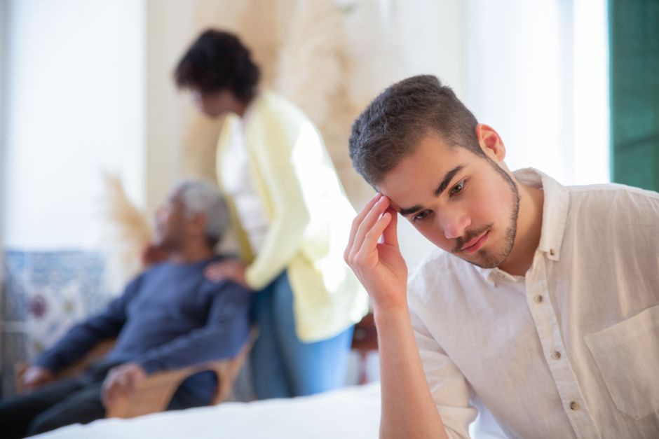A man looks troubled as he quietly manages his own family responsibilities in the background.