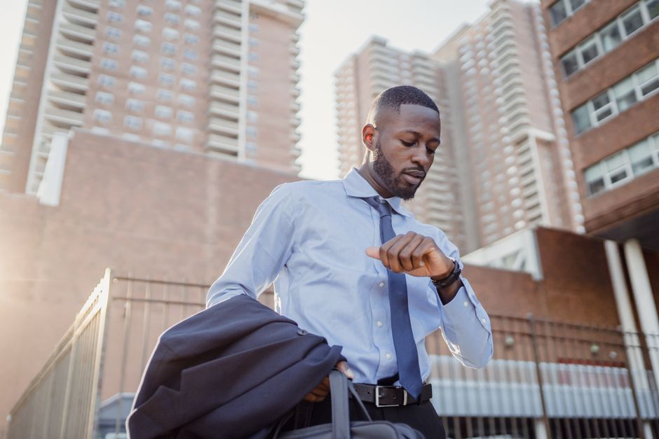 A busy man pausing his hectic schedule to check his watch, making time despite a packed day.