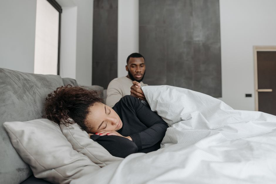 A man watches silently over his tired, sleeping partner, not knowing what words could help.