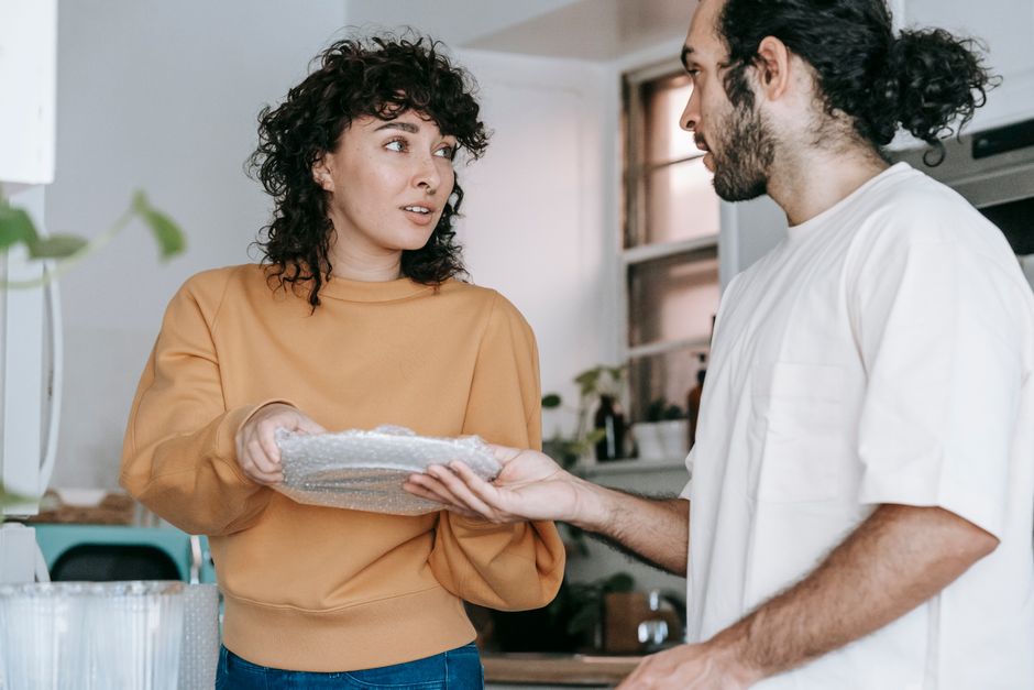 A woman shows her partner something she's done while unpacking, hoping he'll notice her effort.