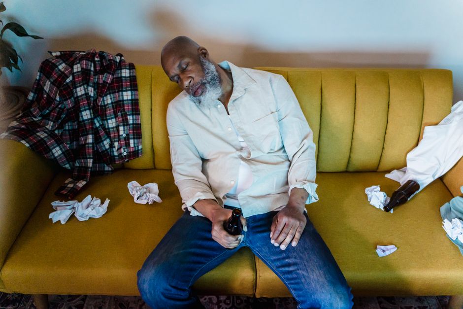 A man caught fast asleep on the couch, beer bottle still in hand, clearly not fooling anyone.