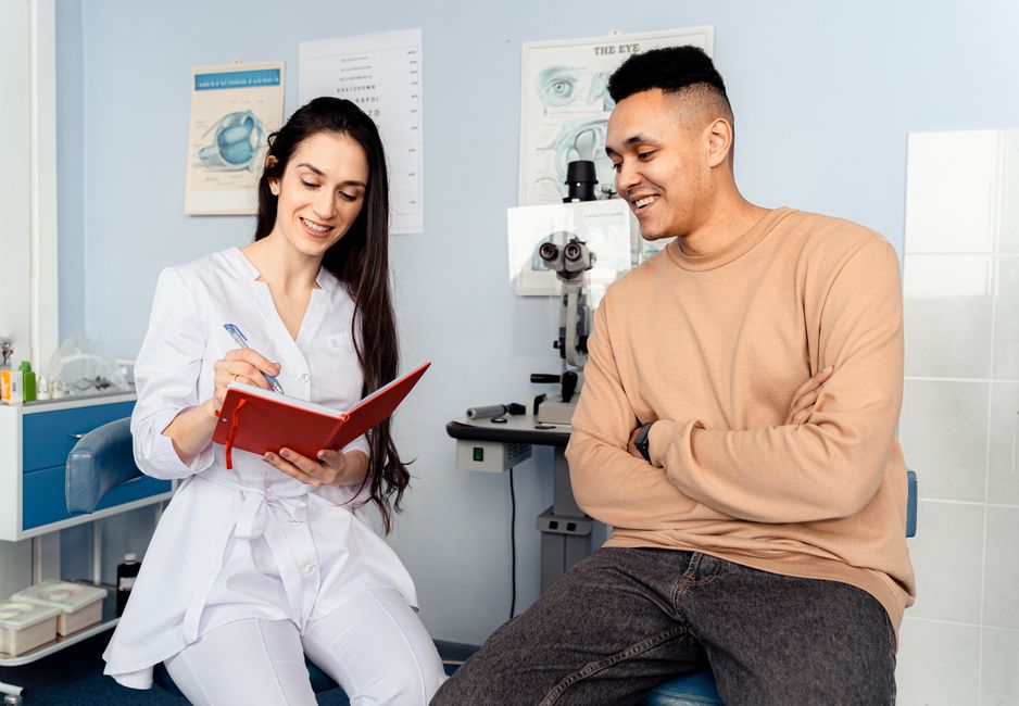 A man cheerfully chats with his doctor during a checkup, perhaps spinning the same tales he tells at home.