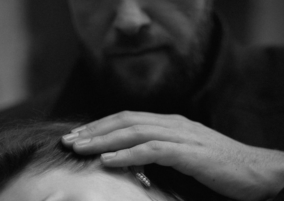 A man softly touches a woman's hair in passing, a quiet gesture of affection that doesn't lead anywhere else.