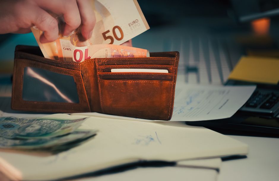 A man keeping his finances in order by securing money in his wallet, symbolizing financial responsibility and loyalty in relationships.