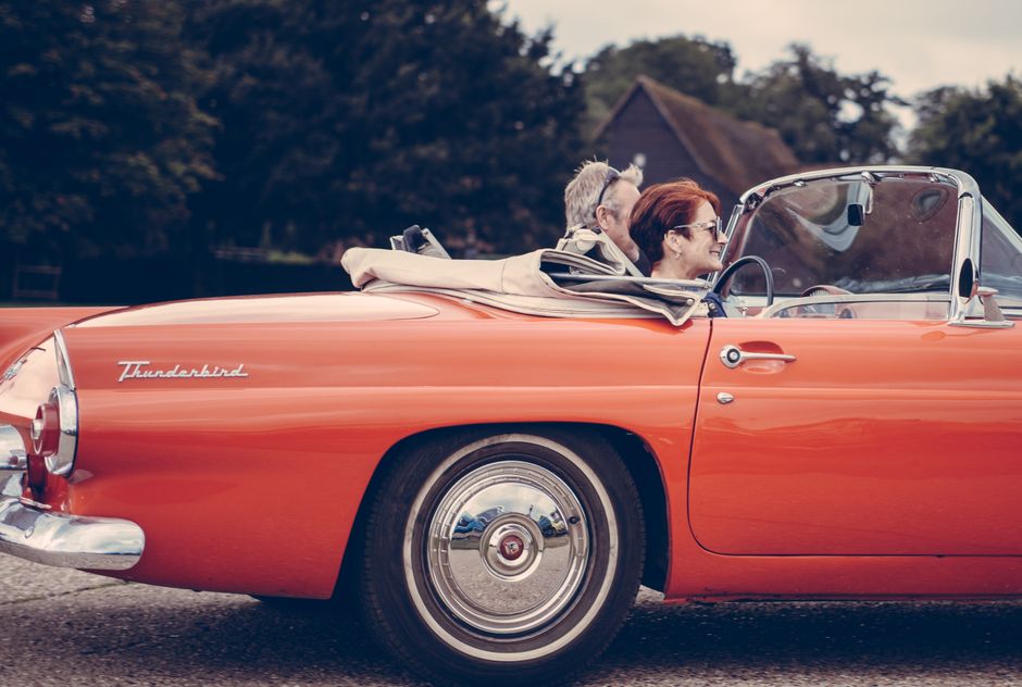 An older man drives his wife in a classic convertible, representing the small acts of devotion that keep couples together for decades.